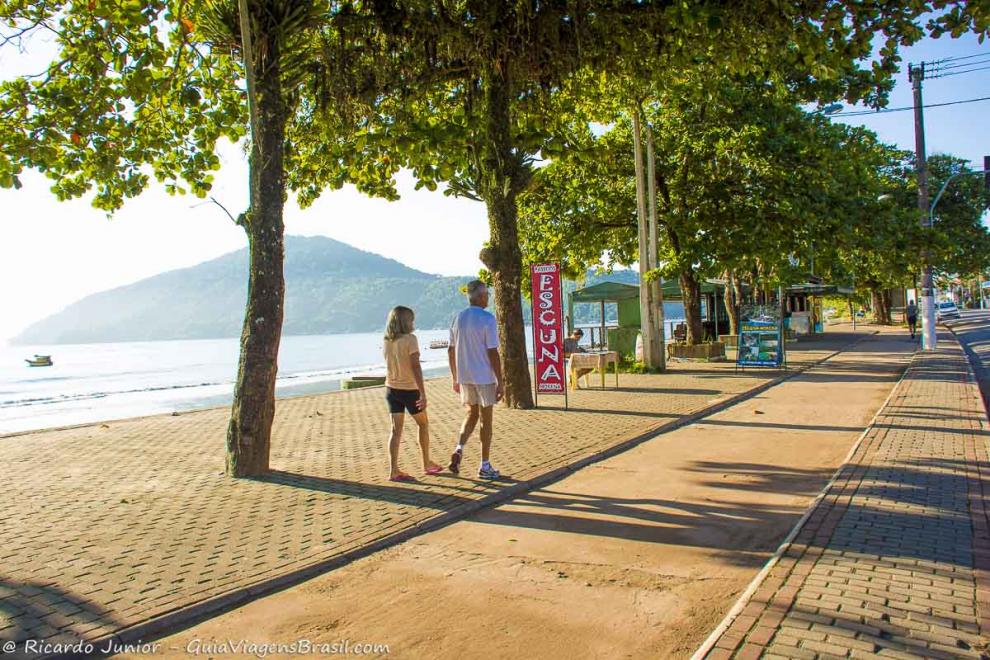 Imagem de quiosques e casal na orla da praia.